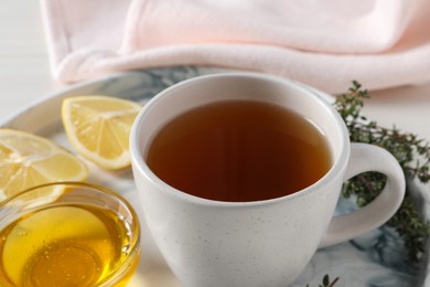 Photo of Aromatic herbal tea with thyme, honey and lemons on tray, closeup