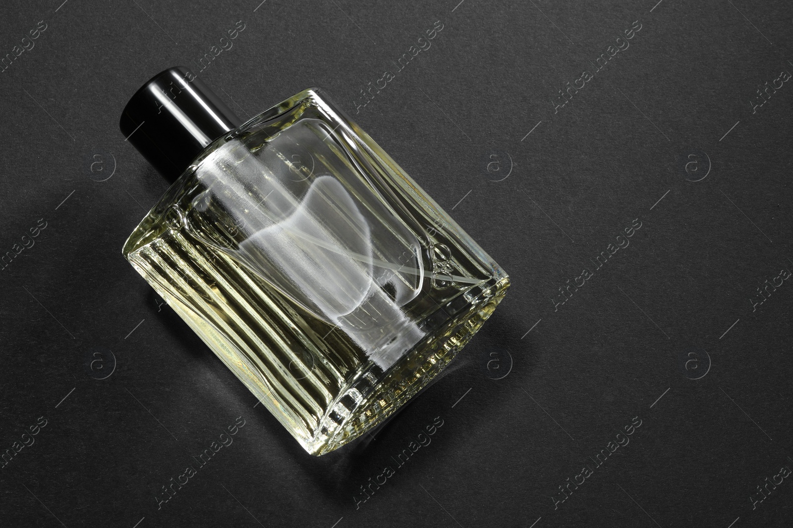 Photo of Luxury men`s perfume in bottle on black background, above view. Space for text