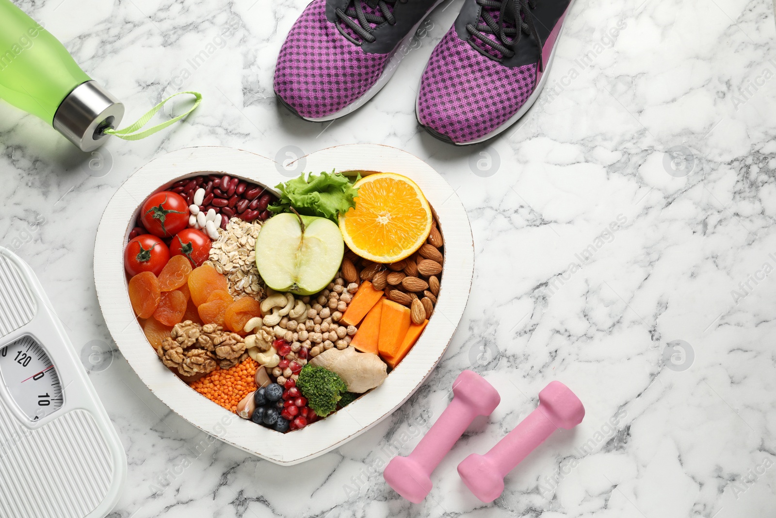 Photo of Heart shaped tray with healthy products and sports equipment on marble background, flat lay. Space for text