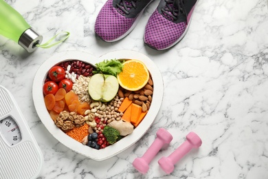 Photo of Heart shaped tray with healthy products and sports equipment on marble background, flat lay. Space for text