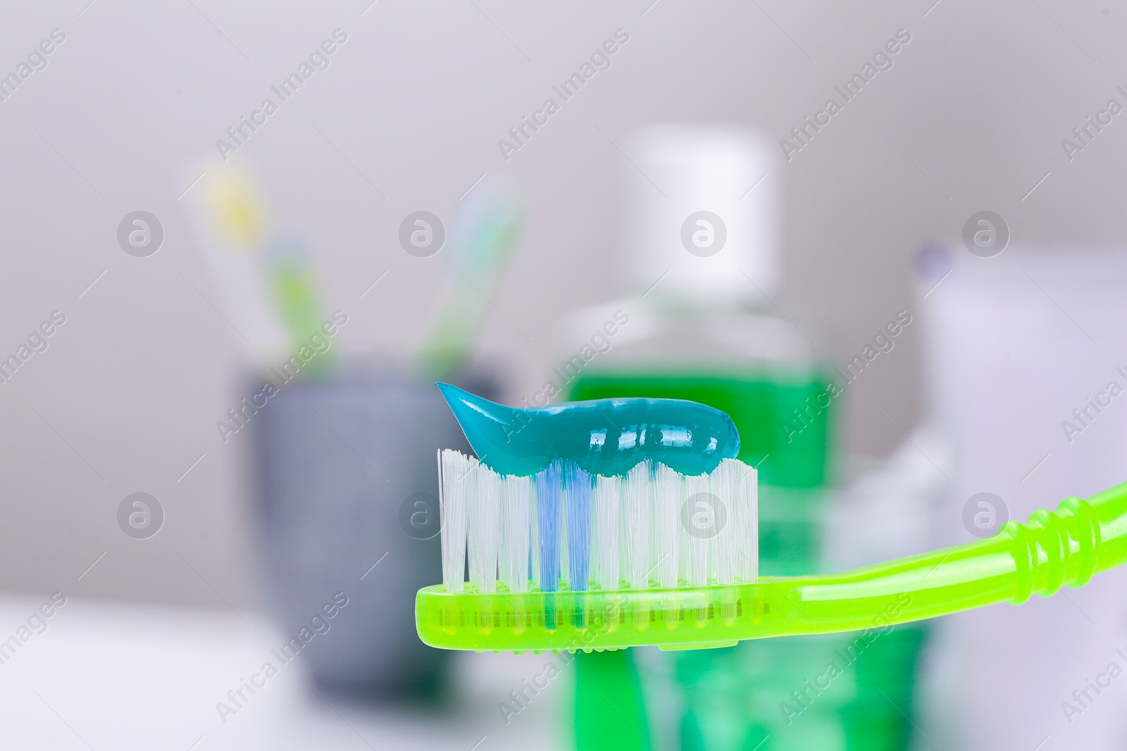 Photo of Toothbrush with paste near mouthwash on blurred background, closeup