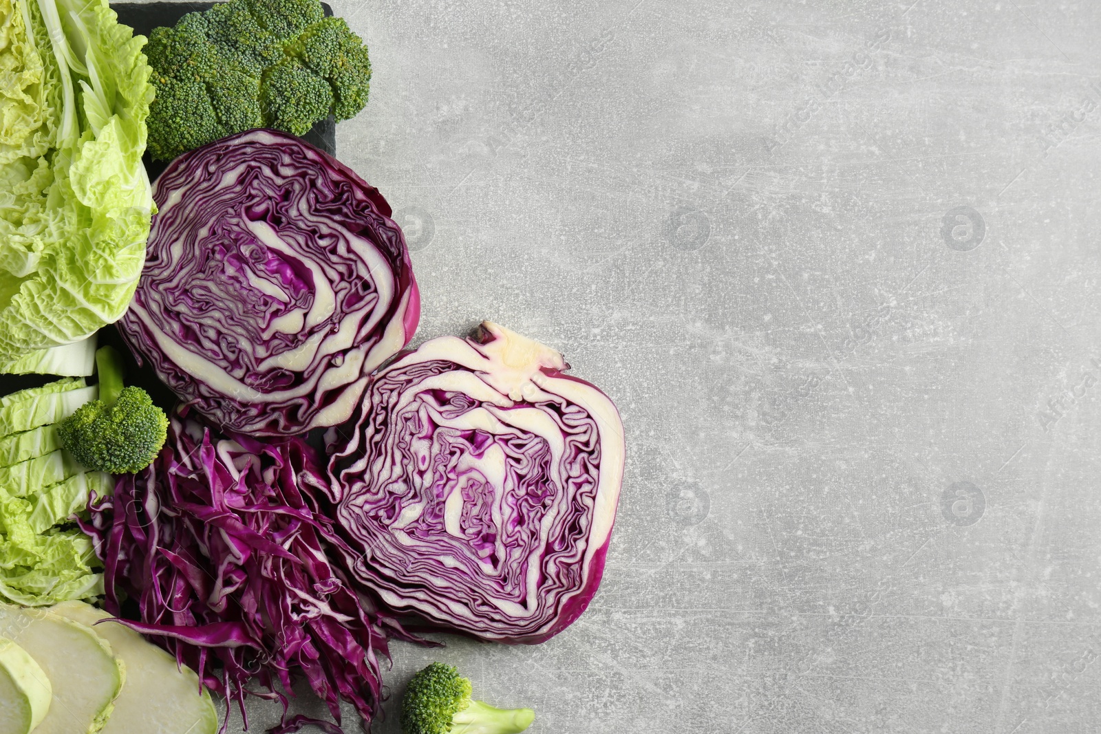 Photo of Different types of cut cabbage on light grey table, flat lay. Space for text