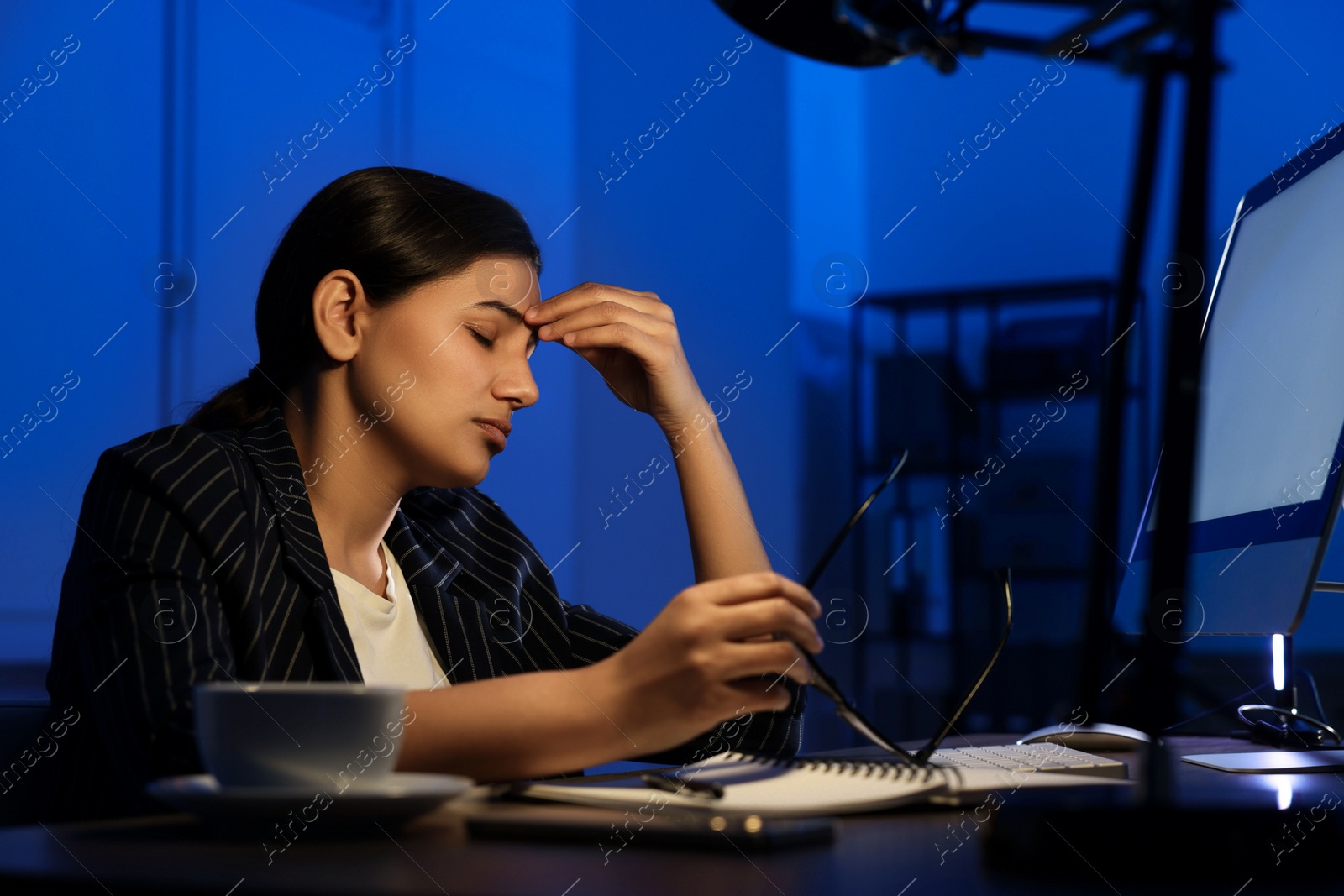 Photo of Tired overworked businesswoman at night in office