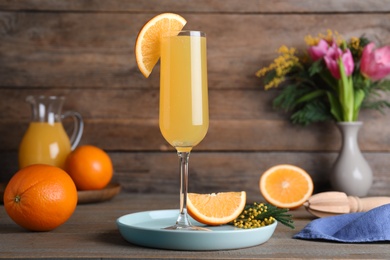 Glass of Mimosa cocktail with garnish on wooden table