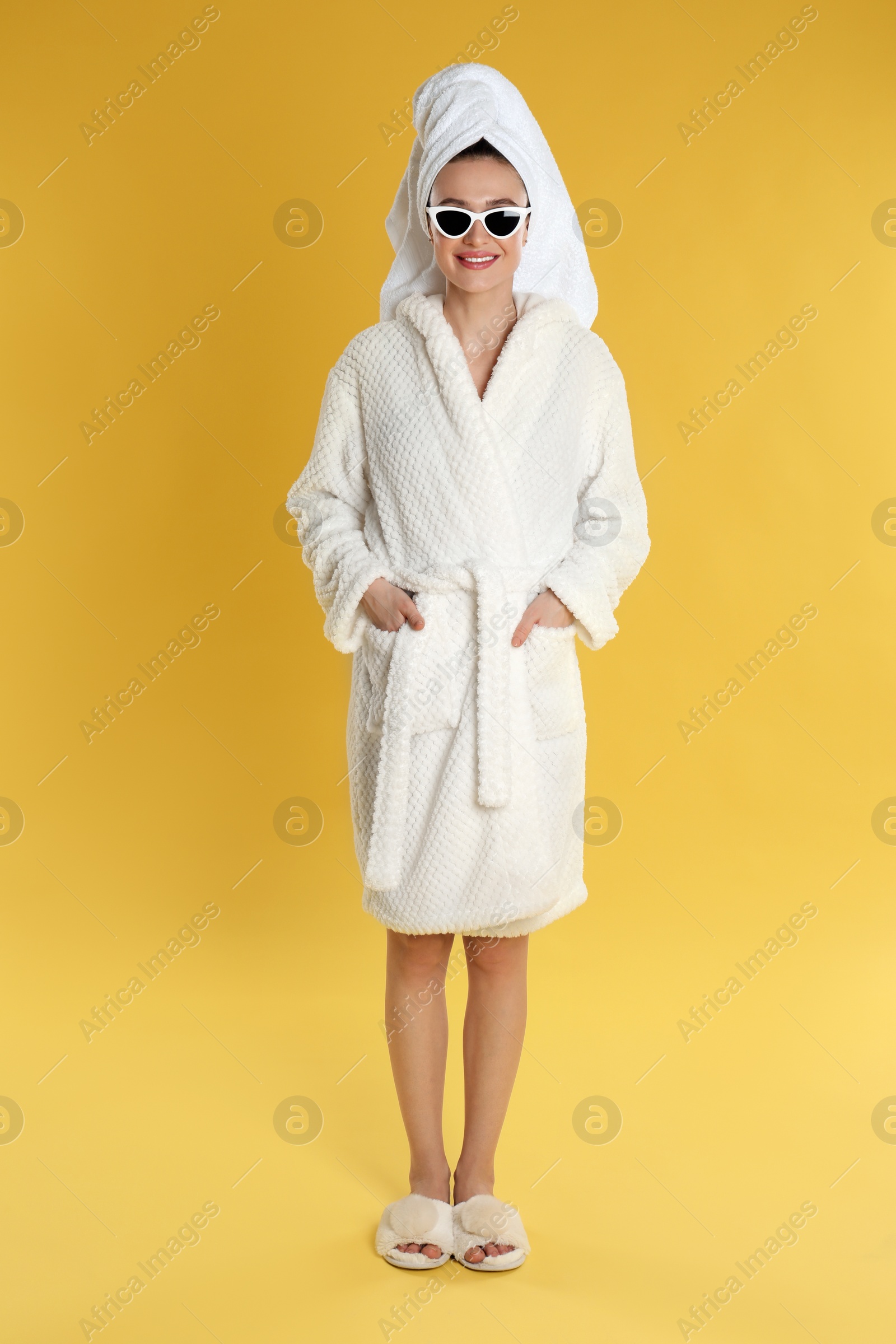 Photo of Beautiful young woman in bathrobe and sunglasses on yellow background