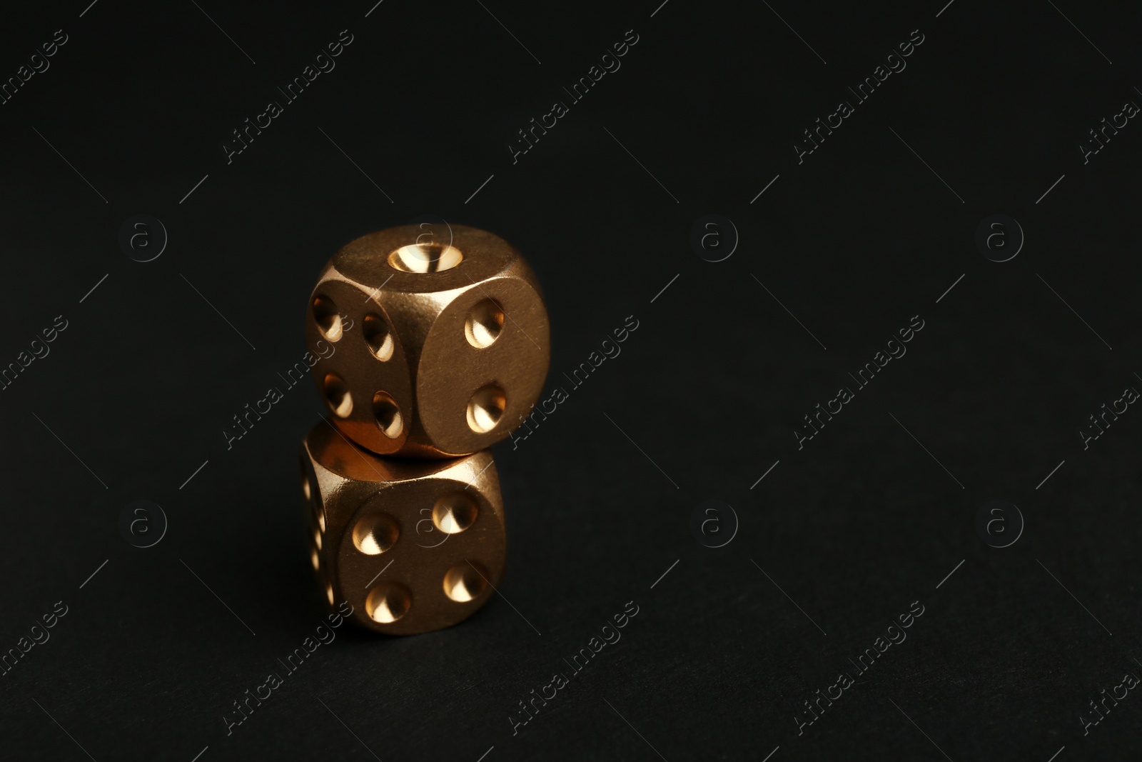 Photo of Stacked gold dices on black background. Space for text
