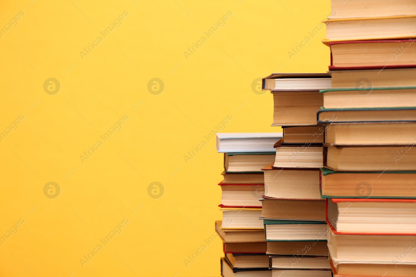 Photo of Many hardcover books on orange background, space for text. Library material