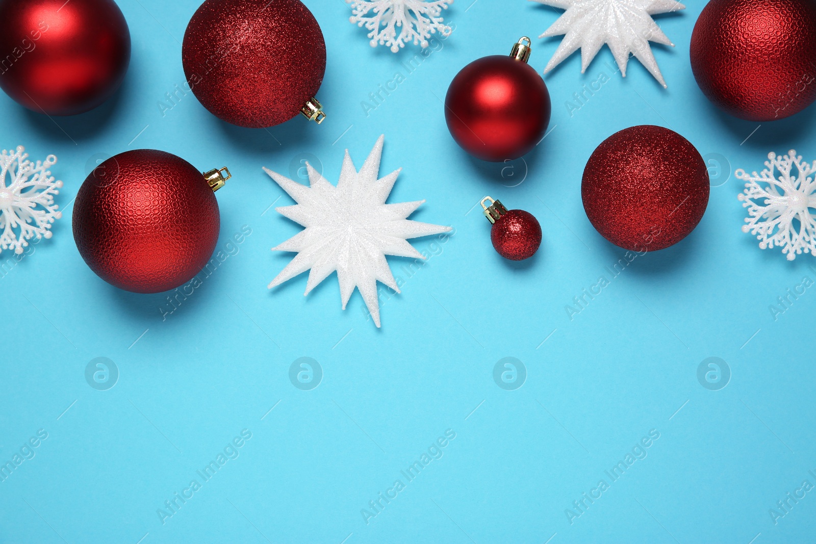 Photo of Red Christmas balls and decorative snowflakes on light blue background, flat lay. Space for text