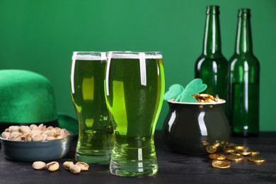 Photo of St. Patrick's day party. Green beer, leprechaun hat, pot of gold and pistachios on wooden table