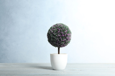 Photo of Artificial plant in flower pot on light grey wooden table