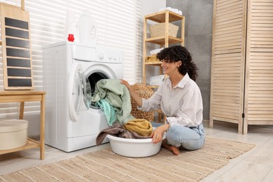 Woman taking laundry out of washing machine indoors