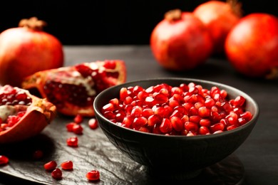 Photo of Tasty ripe pomegranates and grains on dark wooden table, closeup