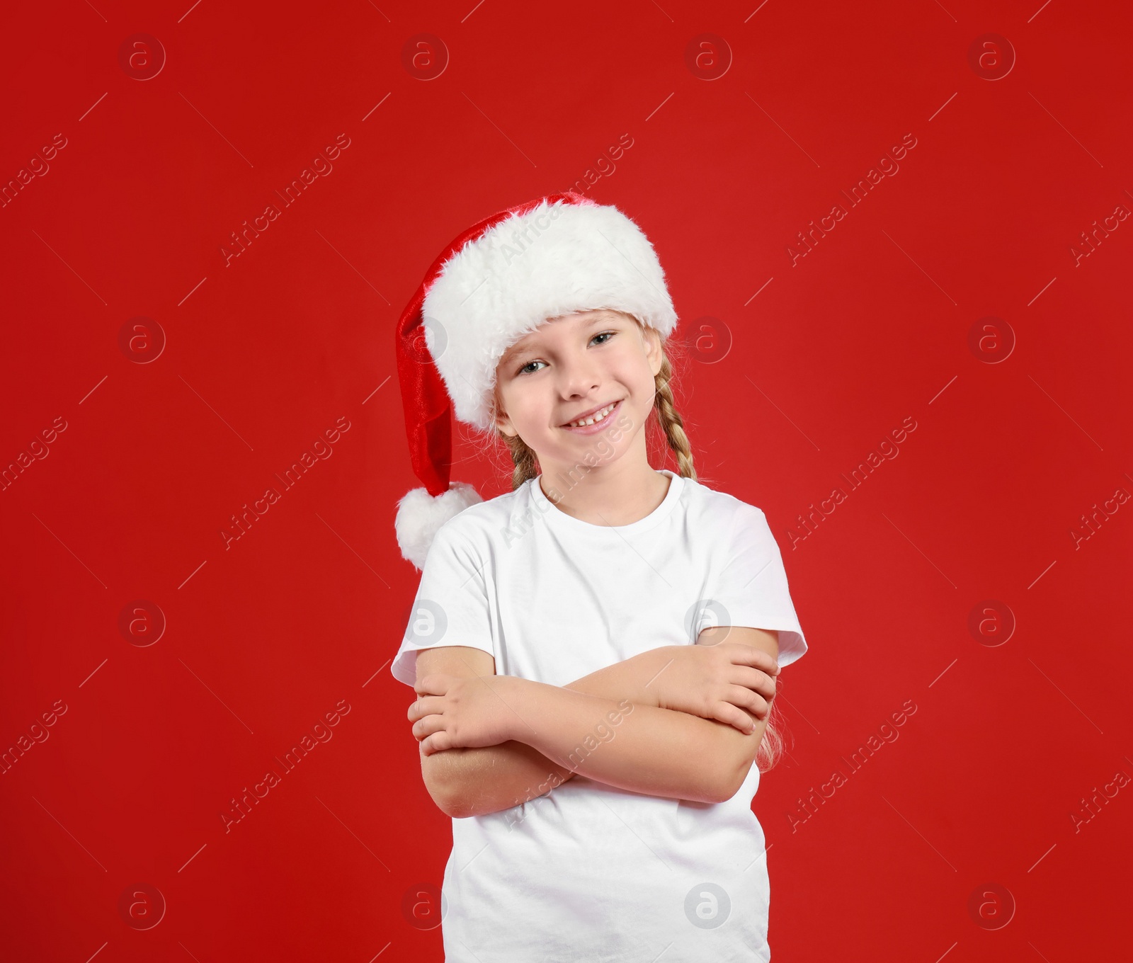 Photo of Cute little child wearing Santa hat on red background. Christmas holiday