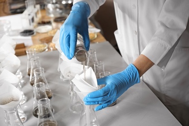 Scientist filtering soil samples at table, closeup. Laboratory analysis