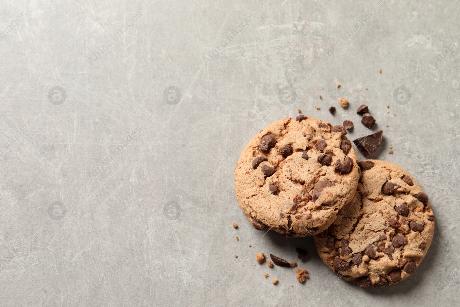 Photo of Two delicious chocolate chip cookies on grey marble table, top view. Space for text