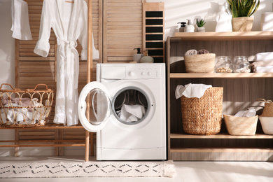 Photo of Modern washing machine and shelving unit in laundry room interior