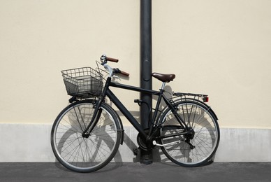 Photo of Vintage bicycle with basket locked to street post outdoors