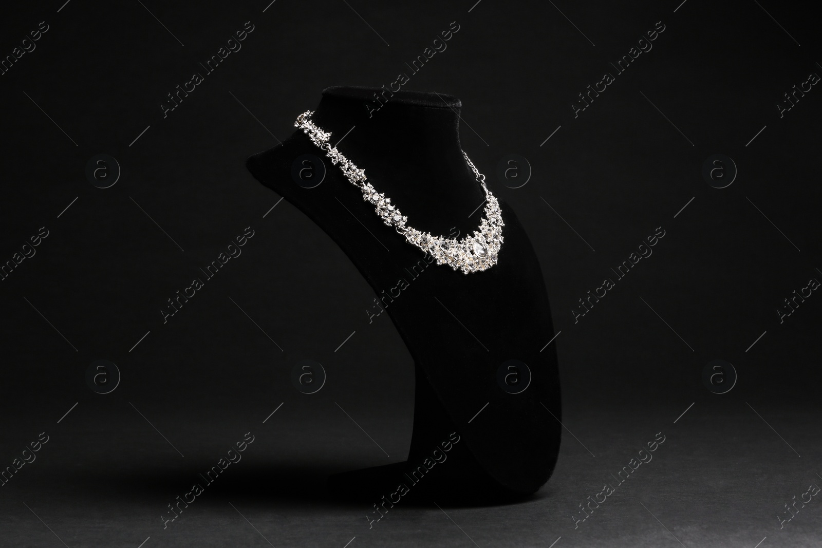 Photo of Elegant necklace on stand against black background. Luxury jewelry