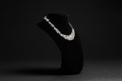 Elegant necklace on stand against black background. Luxury jewelry