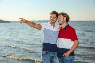 Happy gay couple standing together at riverside
