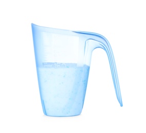 Laundry detergent in plastic measuring cup on white background