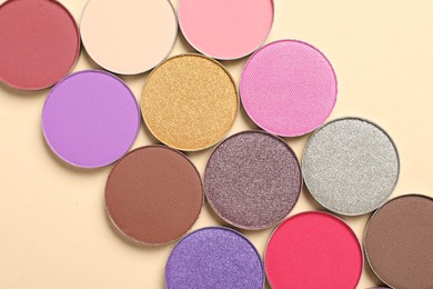 Different beautiful eye shadows on beige background, flat lay