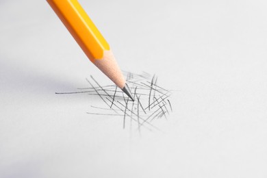 Drawing scribbles with sharp graphite pencil on white background, closeup. Space for text