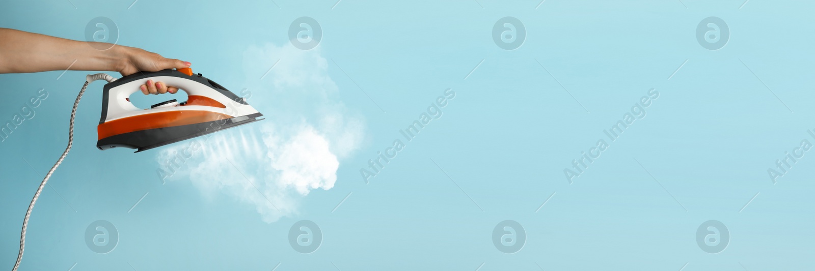 Image of Woman with iron on light blue background, closeup. Banner design with space for text