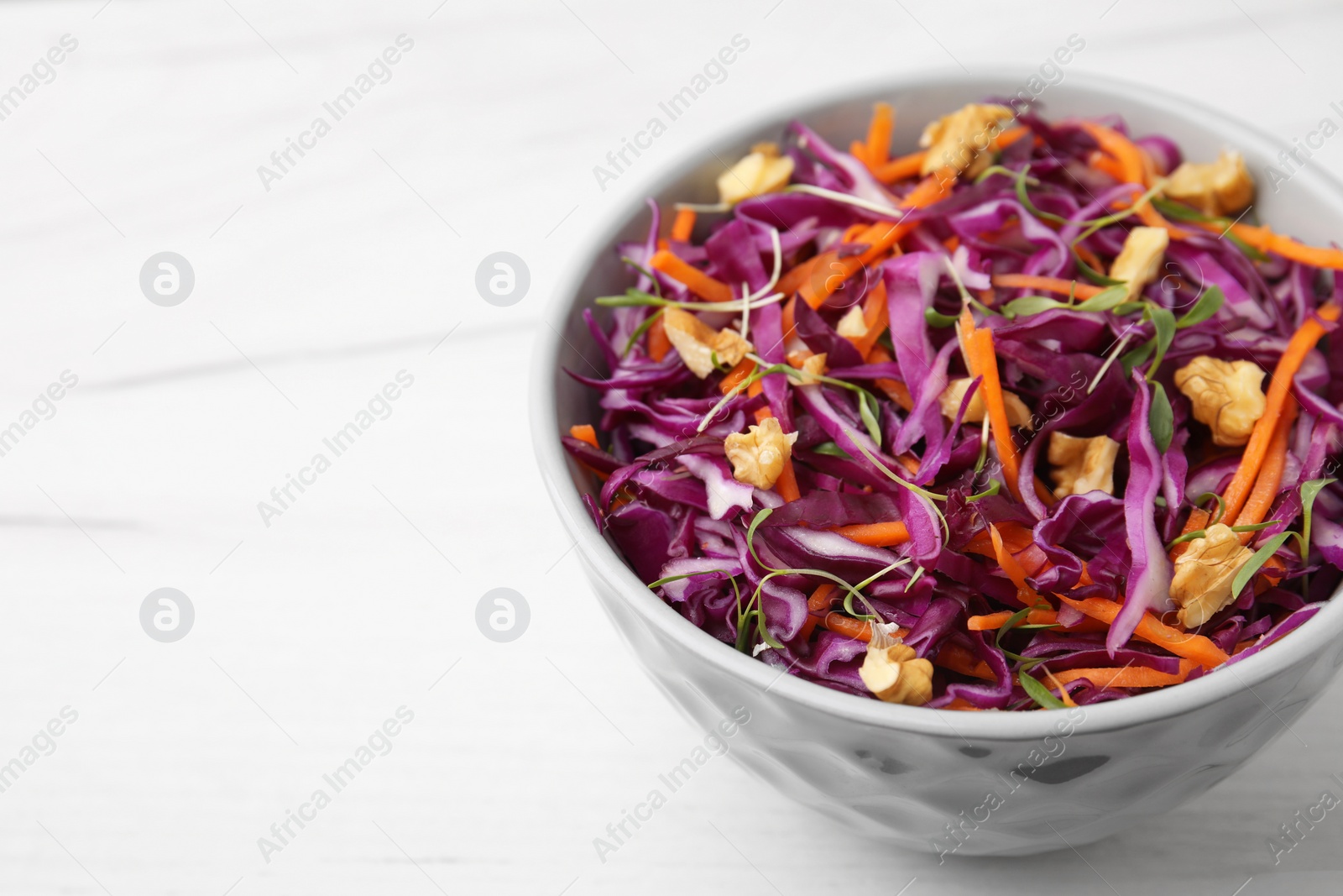 Photo of Tasty salad with red cabbage and walnuts on white wooden table, closeup. Space for text