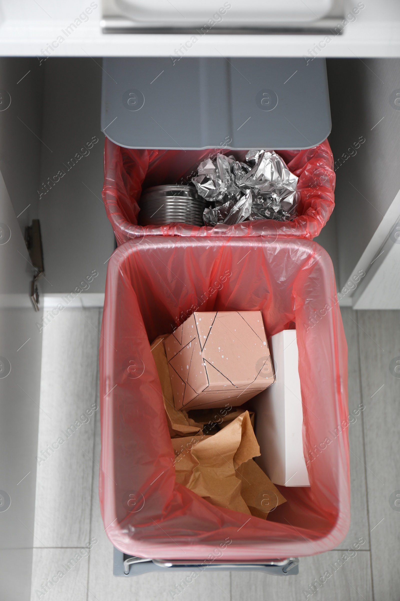 Photo of Open cabinet with full trash bins for separate waste collection in kitchen, top view