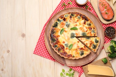 Delicious homemade quiche and ingredients on wooden table, flat lay. Space for text
