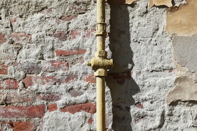 Yellow gas pipe on old brick wall outdoors, space for text