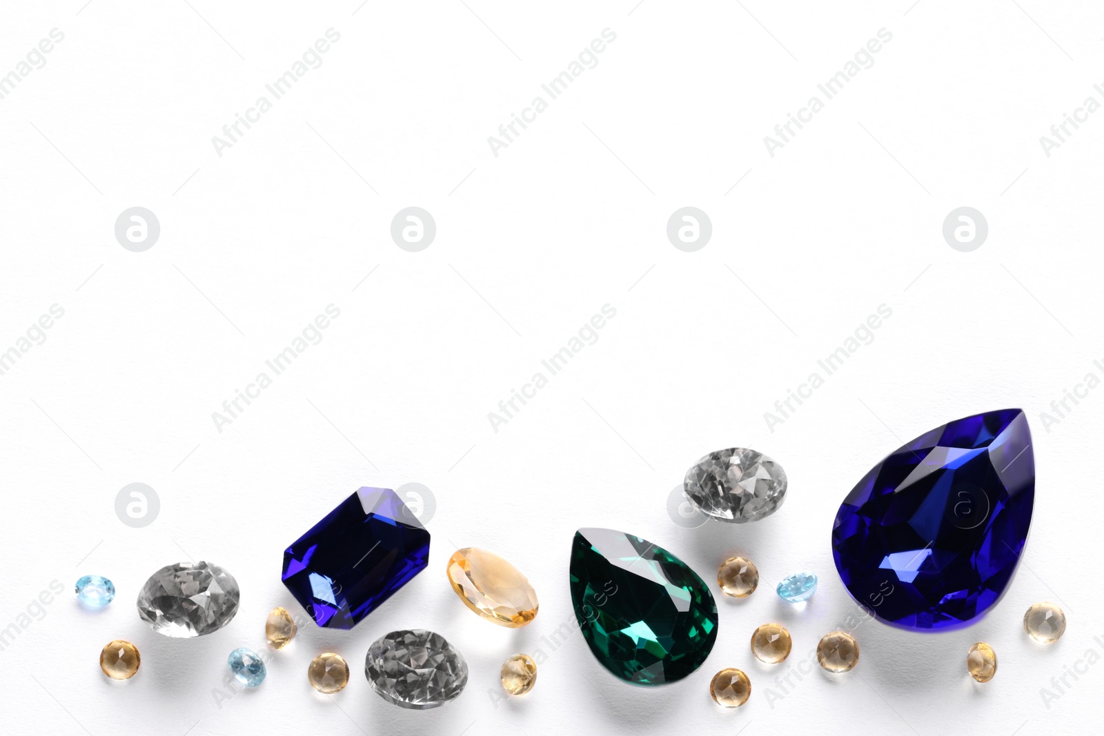 Photo of Different beautiful gemstones for jewelry on white background, top view. Space for text