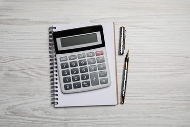 Calculator and office stationery on white wooden table, top view