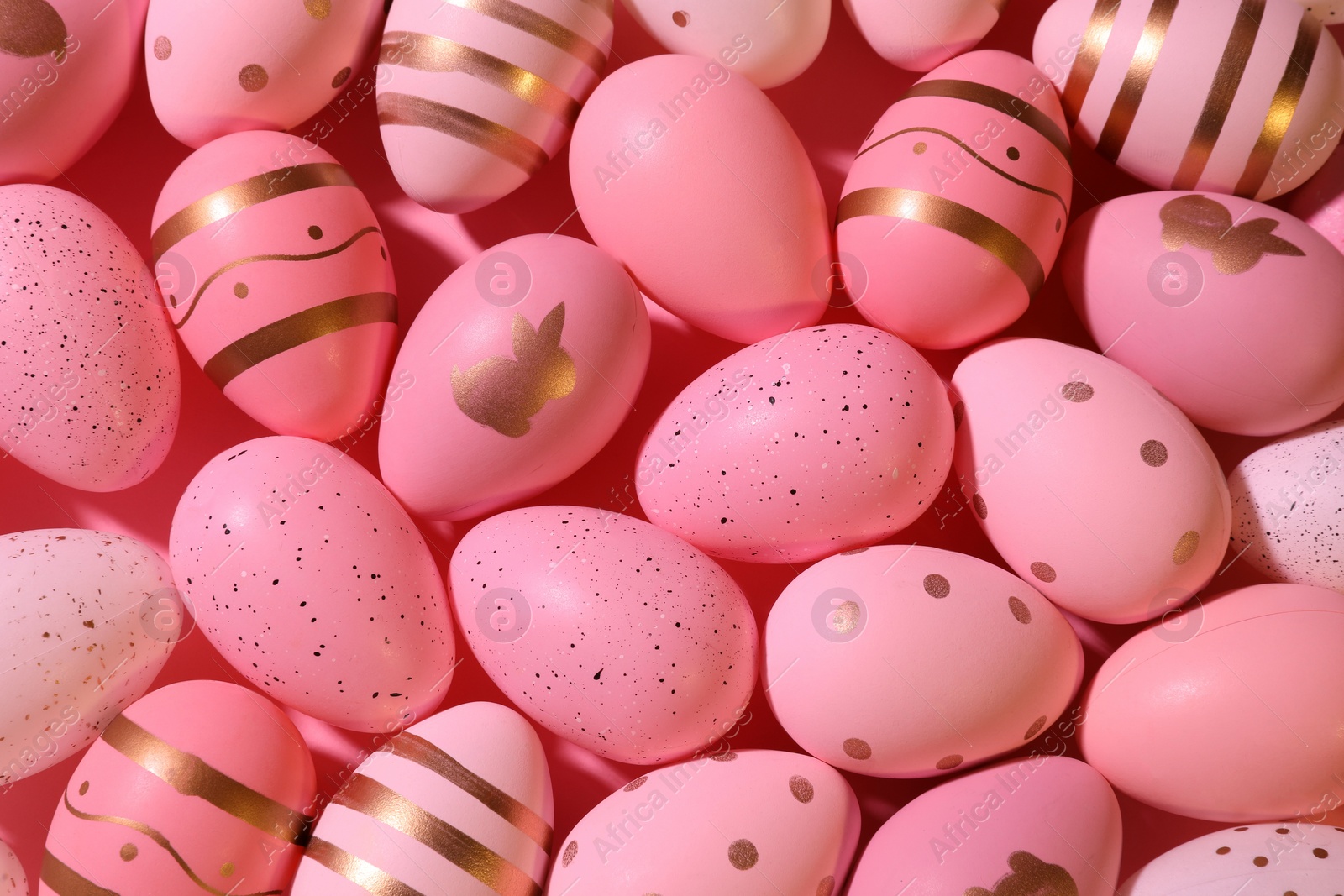 Photo of Many painted Easter eggs on pink background, flat lay