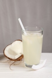 Photo of Glass of coconut water and nut on white wooden table