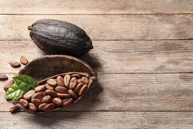 Photo of Composition with cocoa pods and beans on wooden table, above view. Space for text