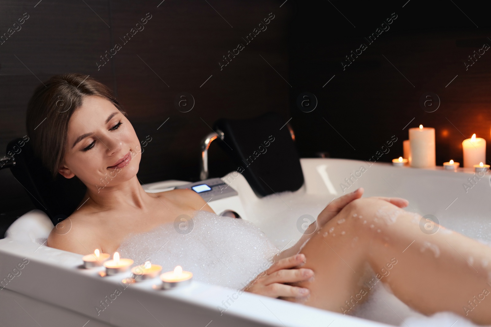 Photo of Beautiful woman taking bubble bath indoors. Romantic atmosphere