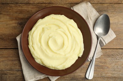 Photo of Freshly cooked homemade mashed potatoes and spoon on wooden table, top view