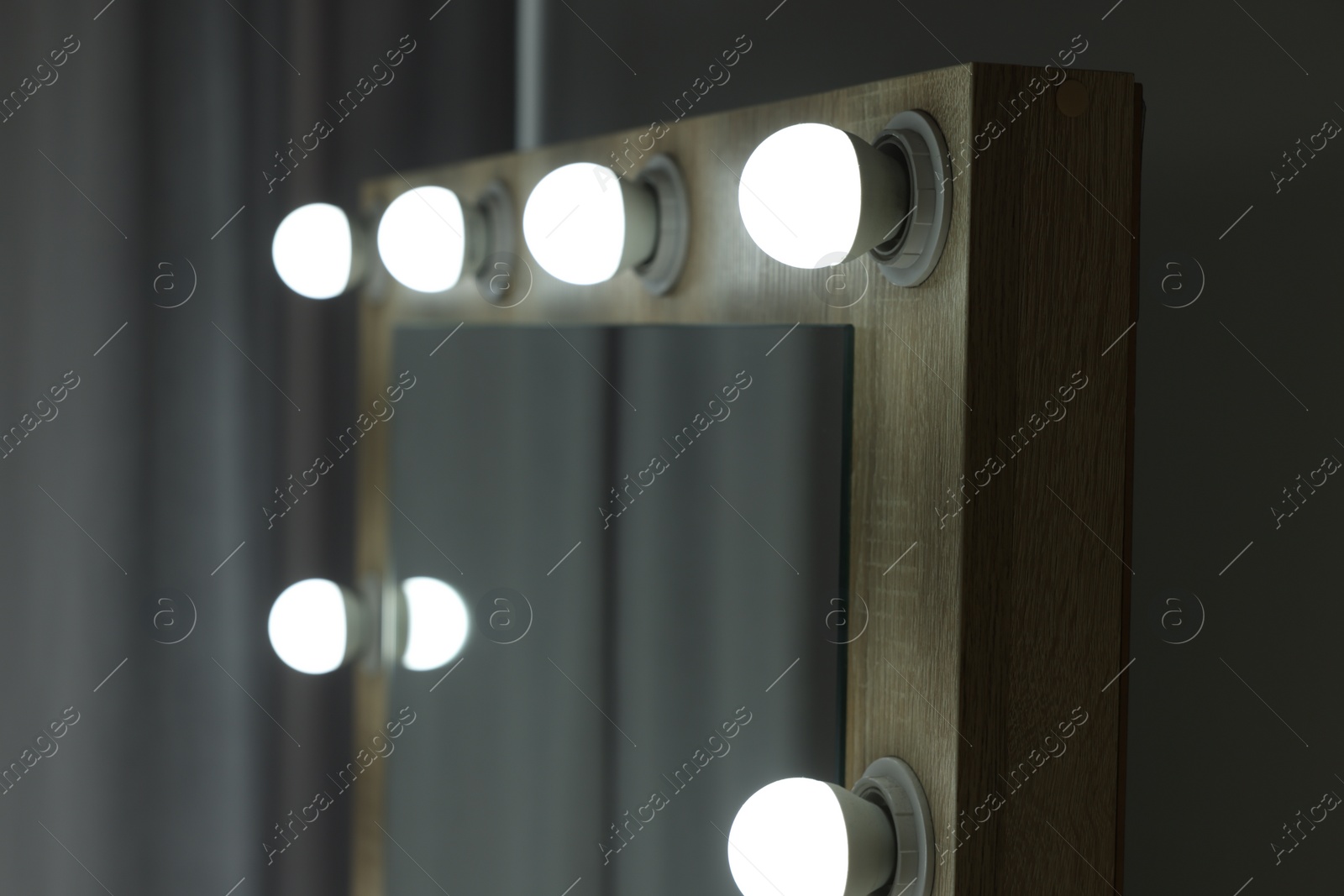 Photo of Beautiful mirror with light bulbs in makeup room, closeup