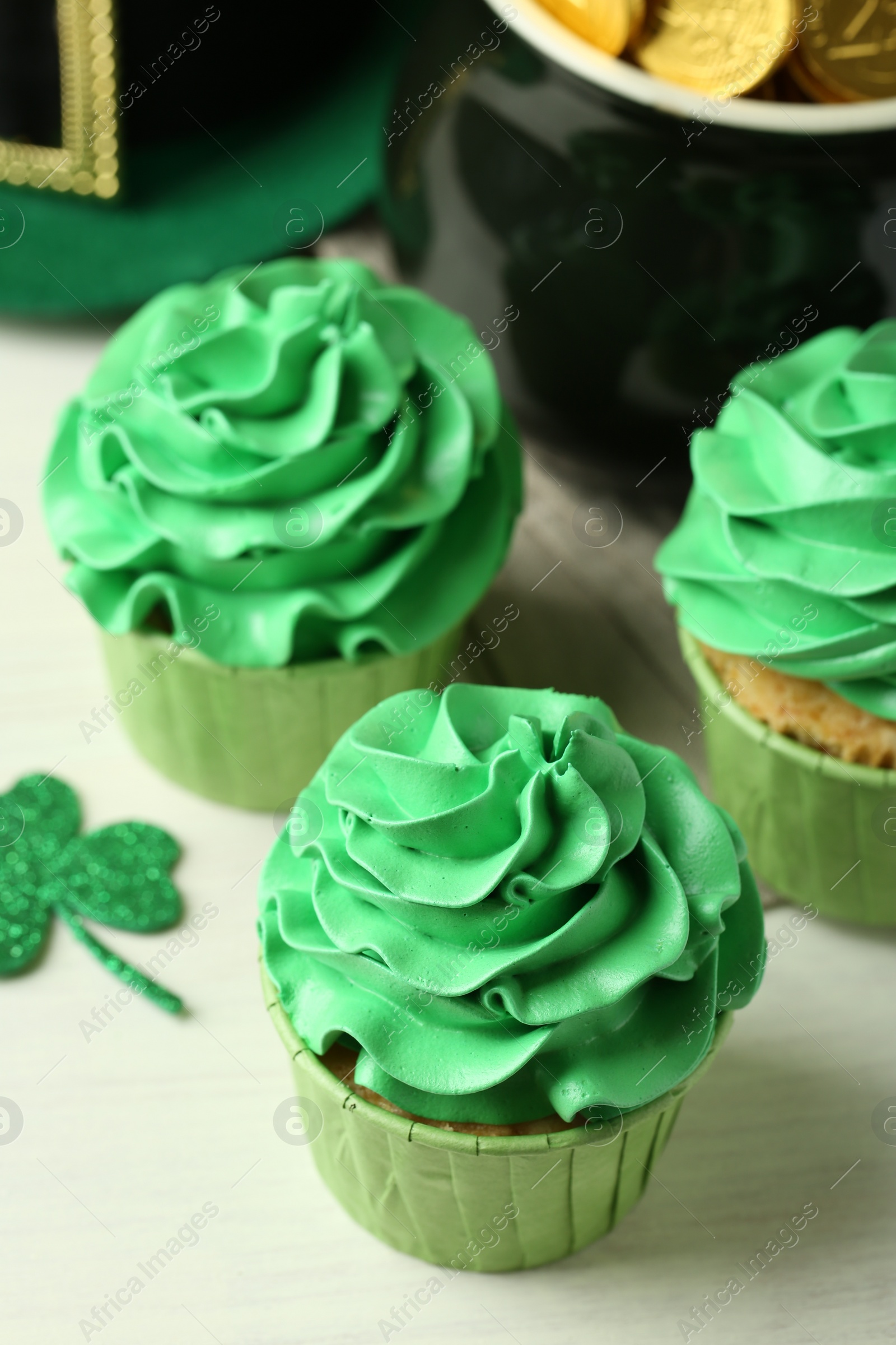 Photo of St. Patrick's day party. Tasty cupcakes with green cream on white table, closeup