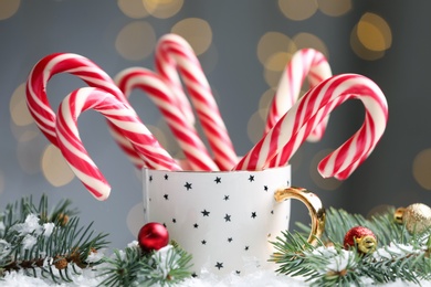 Many sweet candy canes in cup against blurred festive lights. Traditional Christmas treat