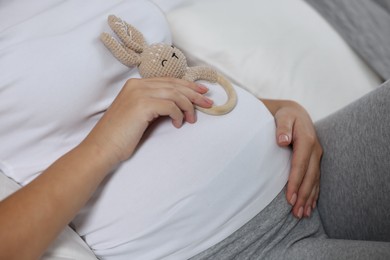 Photo of Pregnant woman with bunny toy lying on bed, closeup