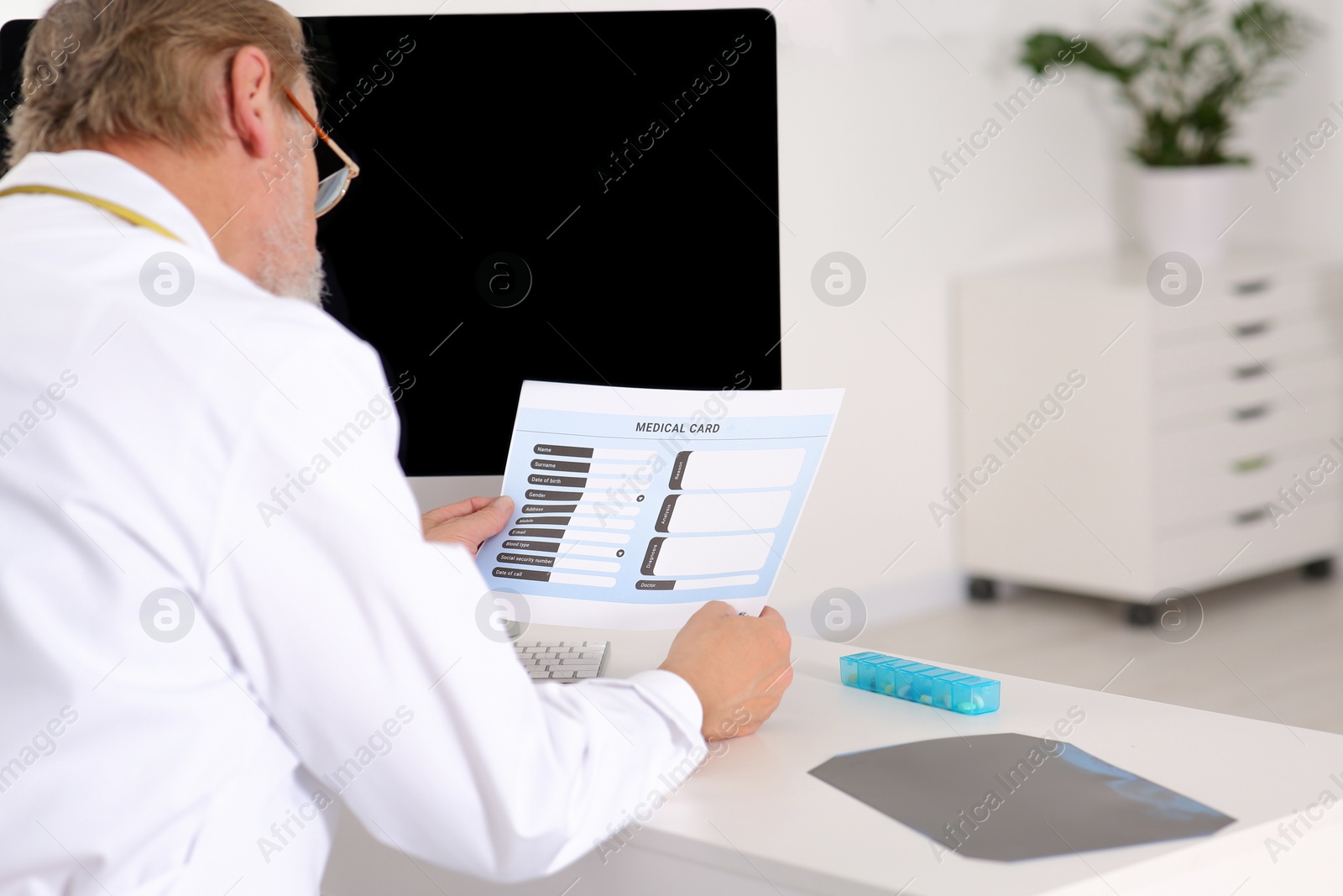 Photo of Doctor with patient's medical card at table in clinic