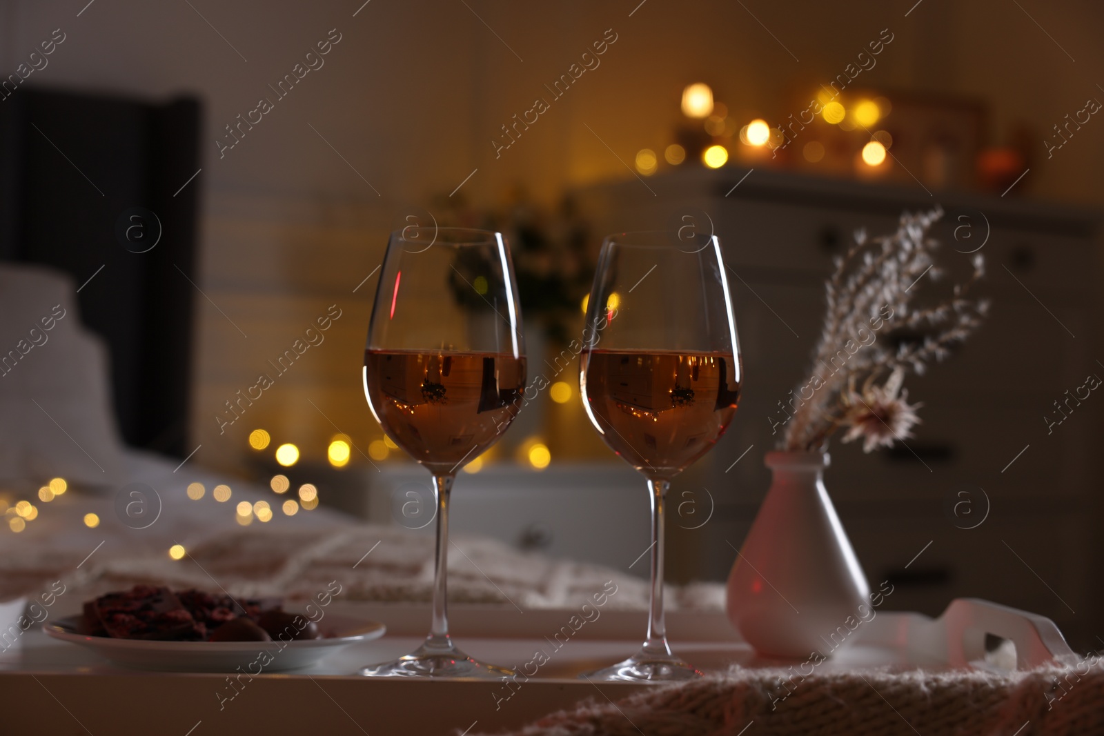 Photo of Glasses of wine in bedroom adorned for romantic evening