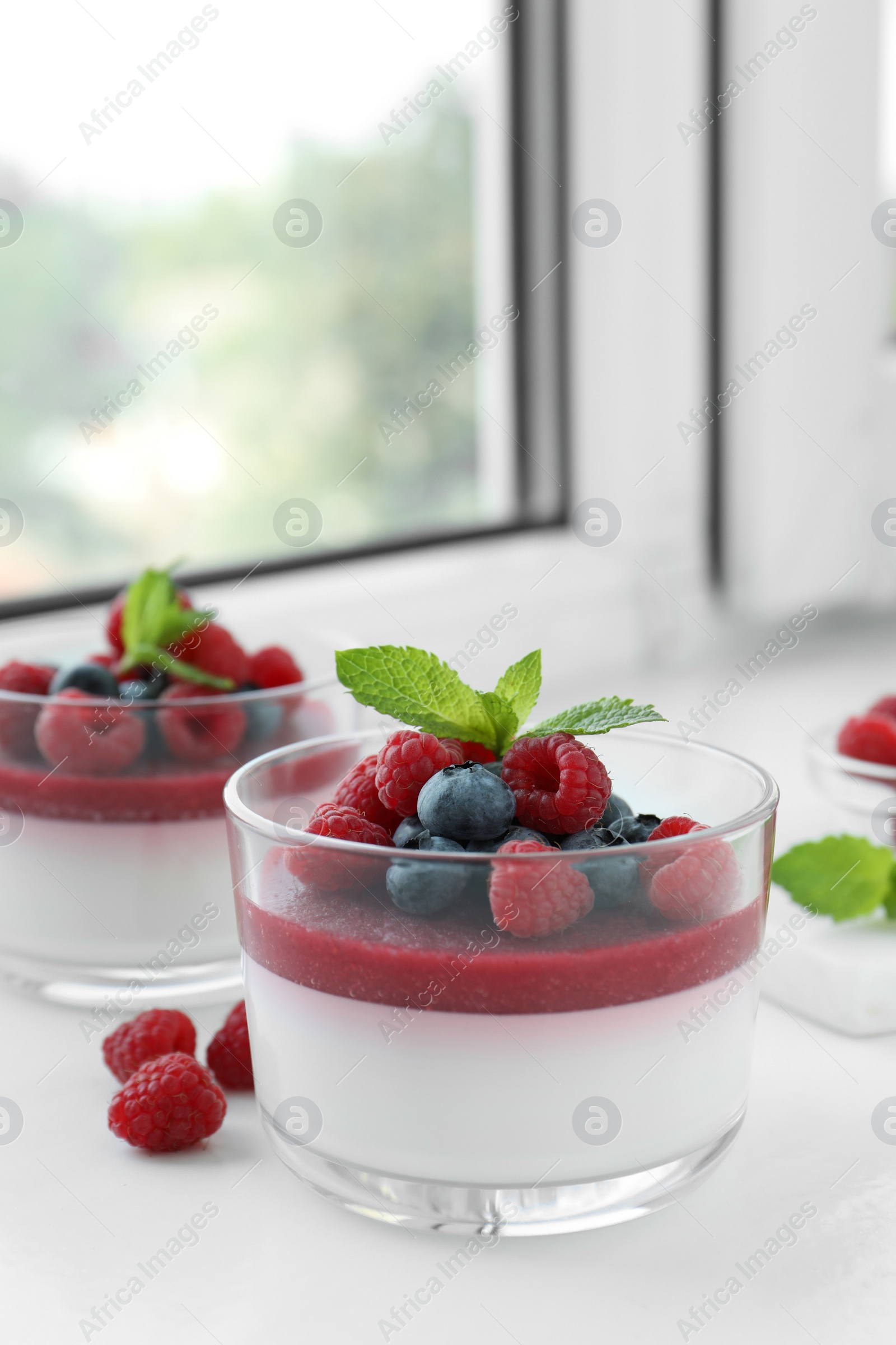 Photo of Delicious panna cotta with berries on window sill