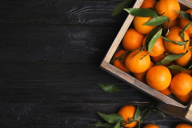 Photo of Crate with fresh ripe tangerines and space for text on wooden background, top view