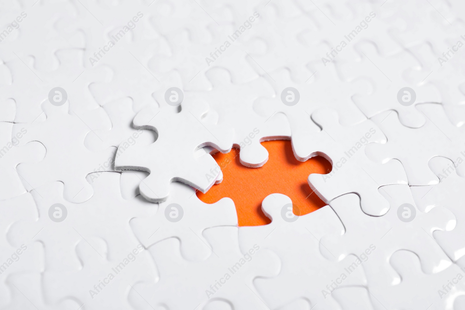 Photo of Blank white puzzle with separated piece on orange background