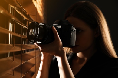 Photo of Private detective with camera spying near window indoors