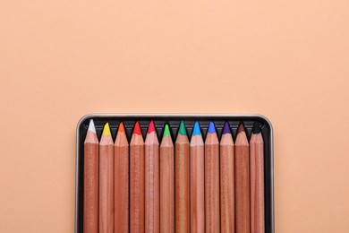 Photo of Colorful pastel pencils in box on beige background, top view with space for text. Drawing supplies